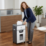 Add smiling woman shredding paper in office